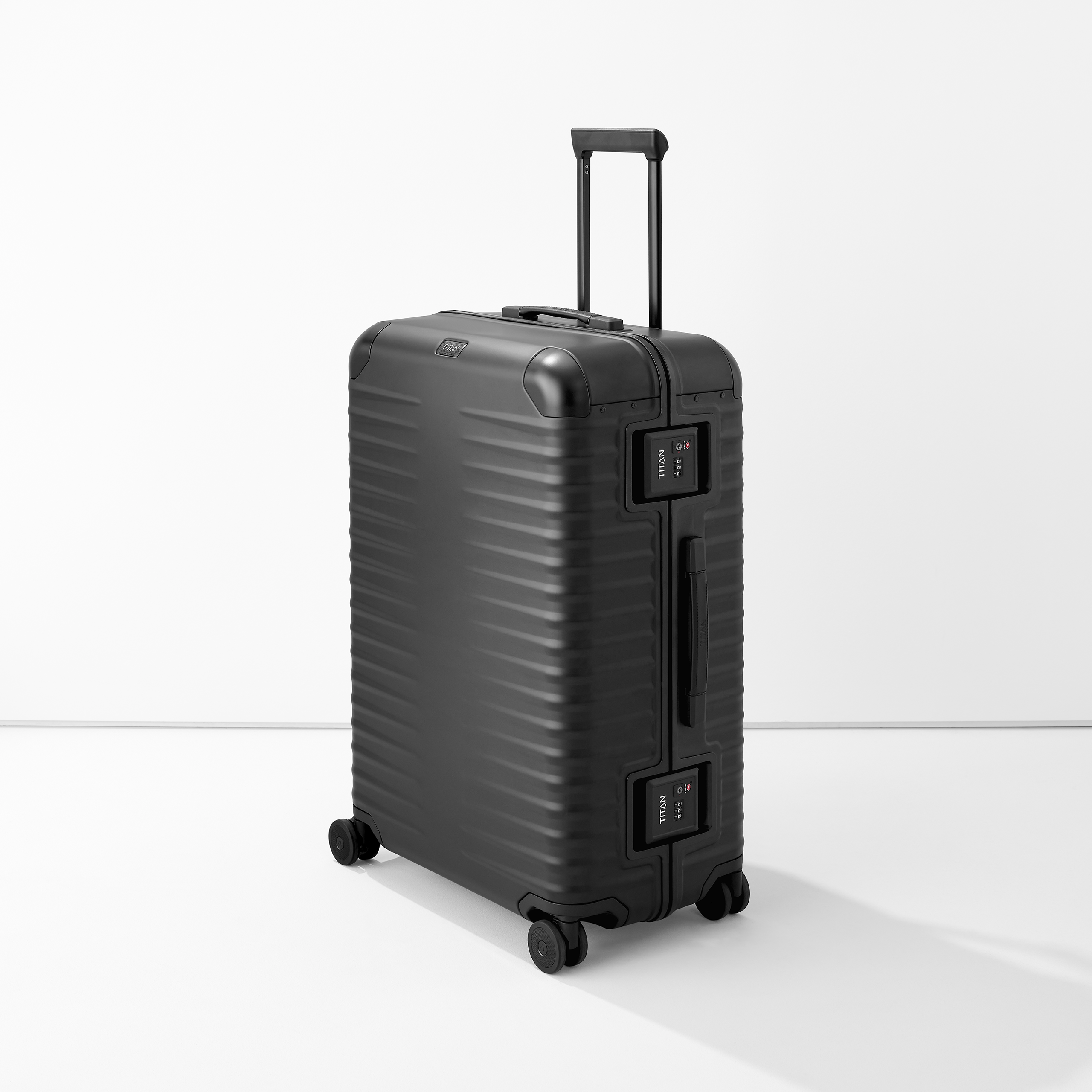 Valise rigide noire à quatre roulettes et poignée télescopique sur fond blanc