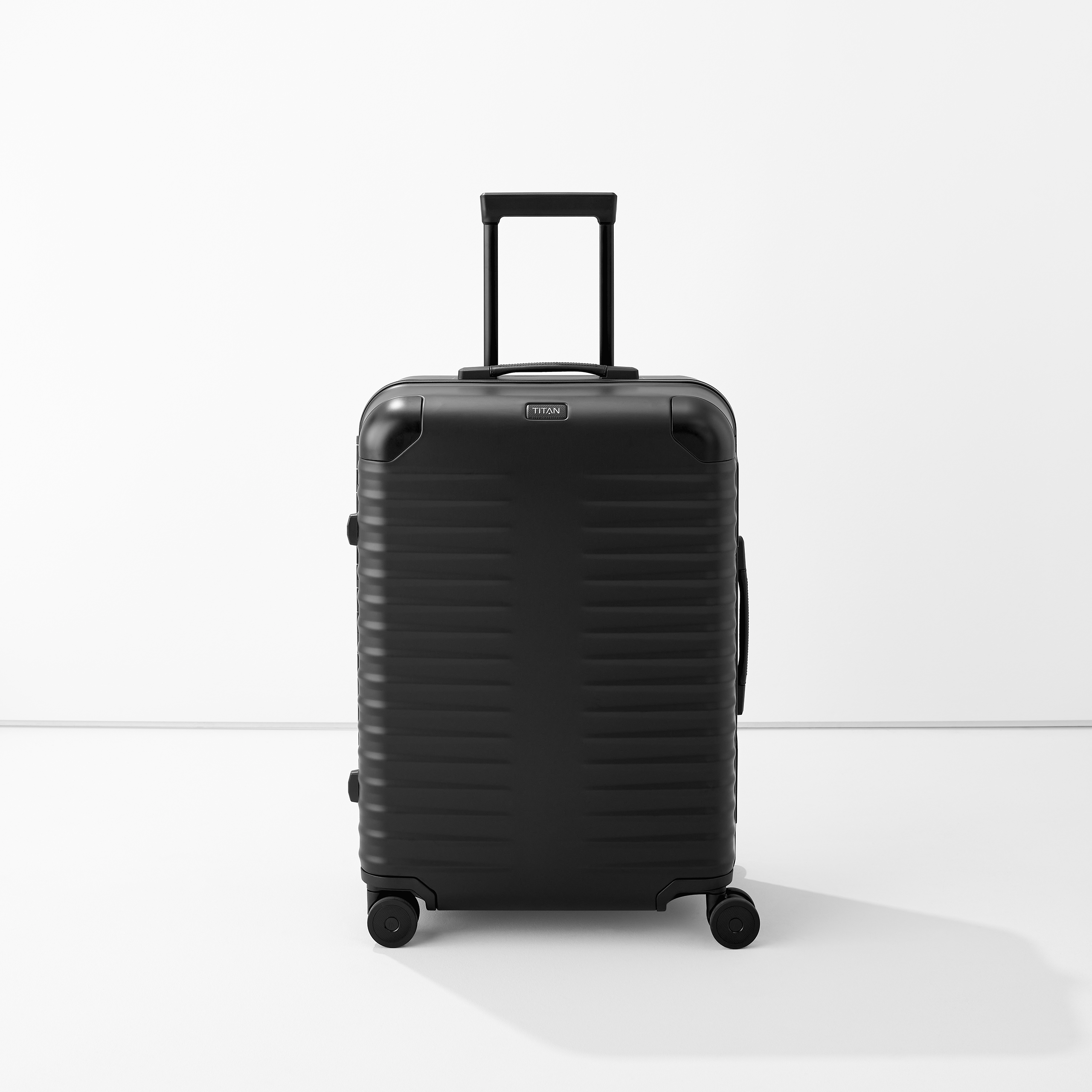 Schwarzer Hartschalenkoffer mit vier Rollen und ausziehbarem Griff, steht auf hellem Boden