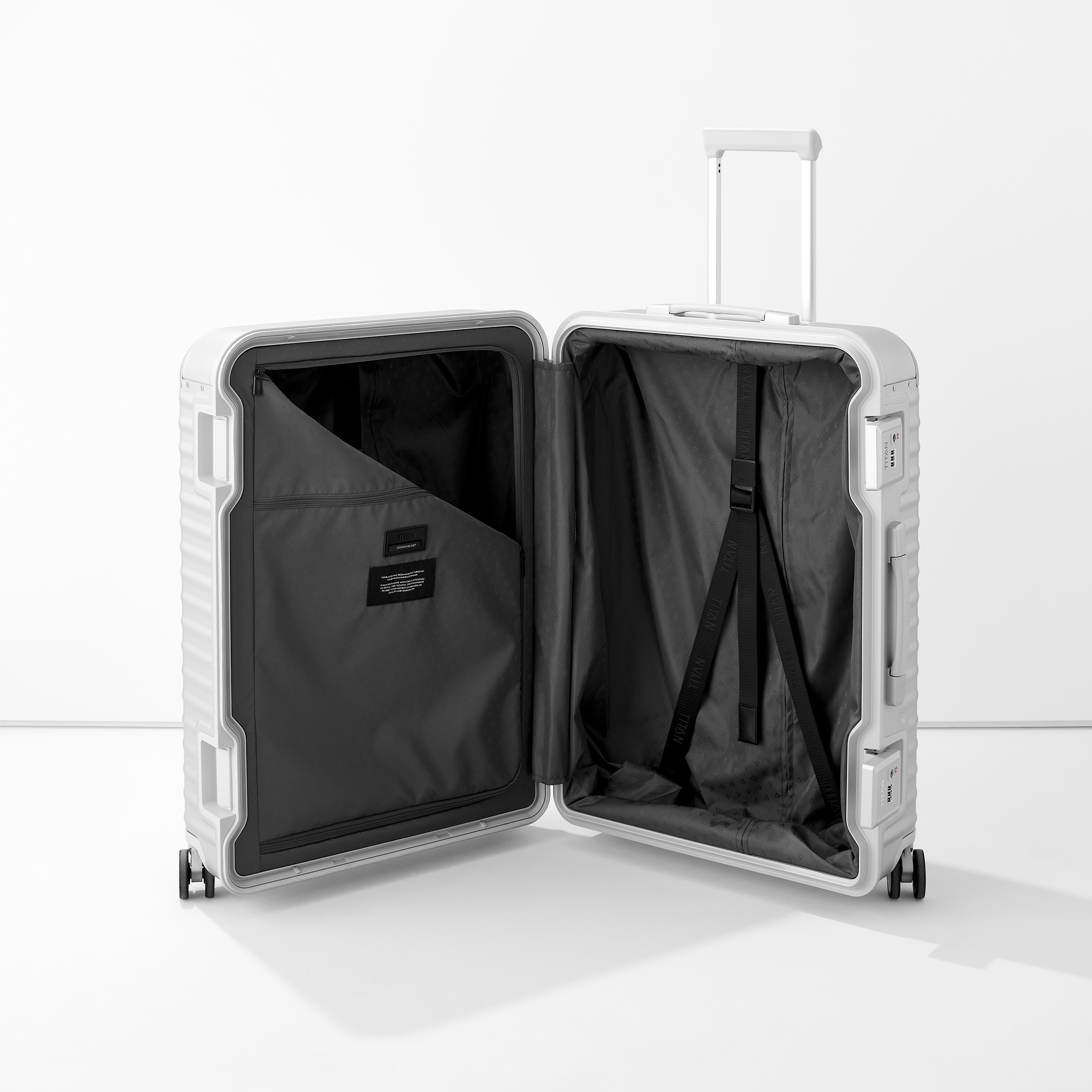 Moderner silberner Aluminium-Koffer mit ausgezogenem Griff und geöffneter Innenseite, inklusive Packgurten und Innentasche Geöffneter weißer Koffer mit schwarzem Innenfutter, praktischen Packgurten und Innentasche für übersichtliches Packen