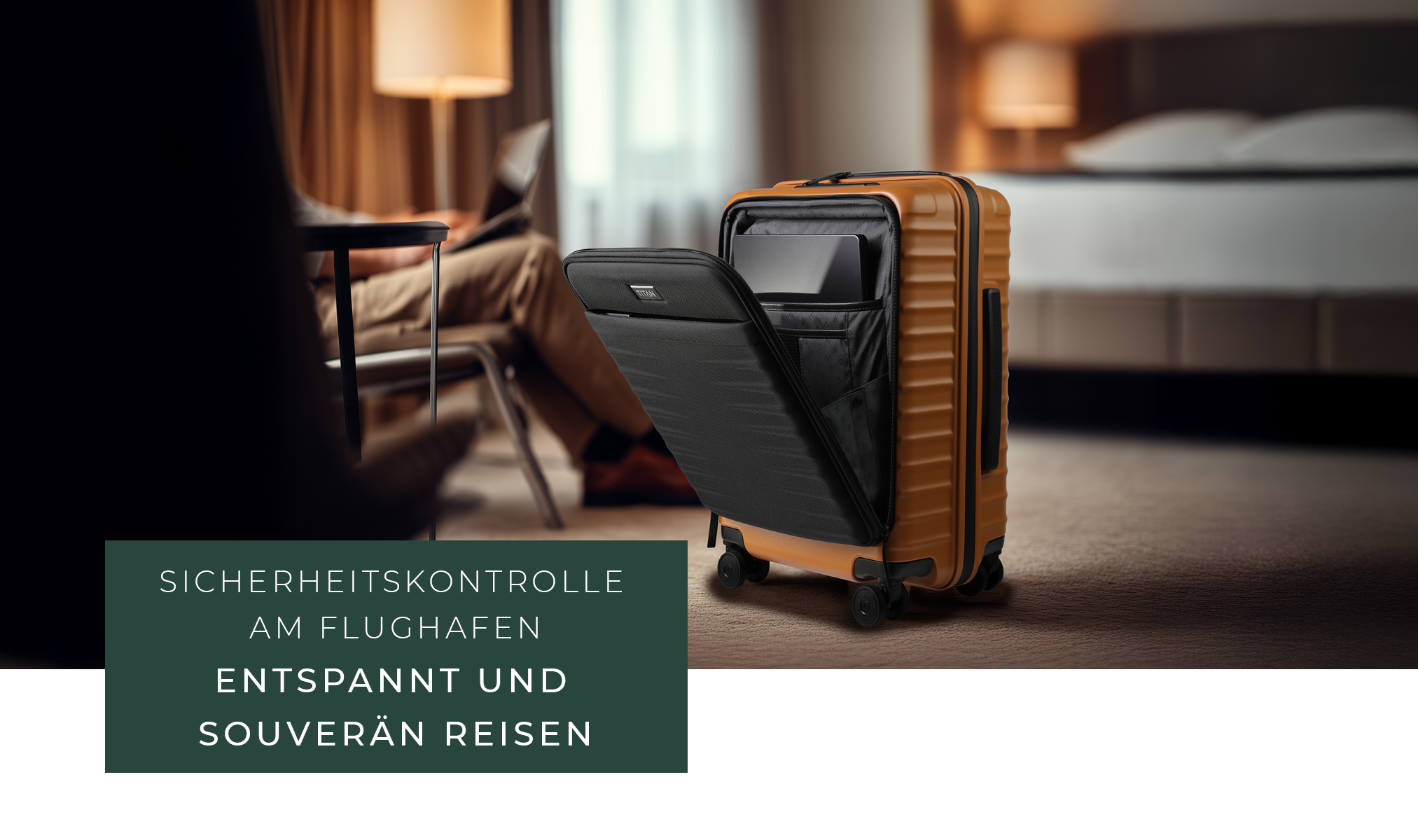 Ein geöffneter, orangefarbener Koffer steht auf einem Teppich. Im Inneren des Koffers ist ein Laptop sichtbar. Im Hintergrund sitzt eine Person an einem Tisch und arbeitet am Laptop. Im Hintergrund ist ein Bett erkennbar.