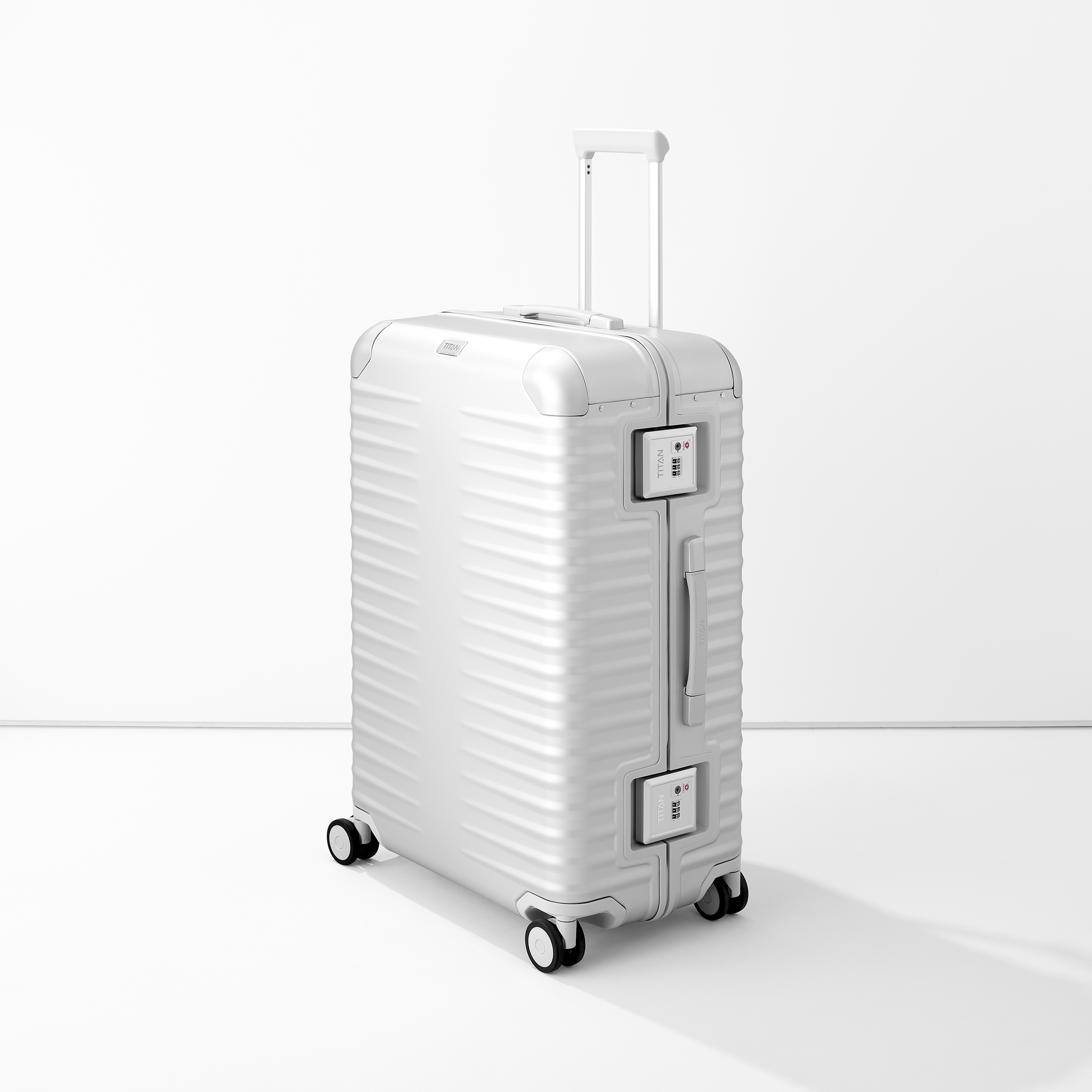 Stabiler Aluminium-Koffer in Silber mit vier Rollen und Teleskopgriff Moderner silberner Aluminium-Koffer mit vier Rollen und integriertem Zahlenschloss, steht aufrecht vor weißem Hintergrund