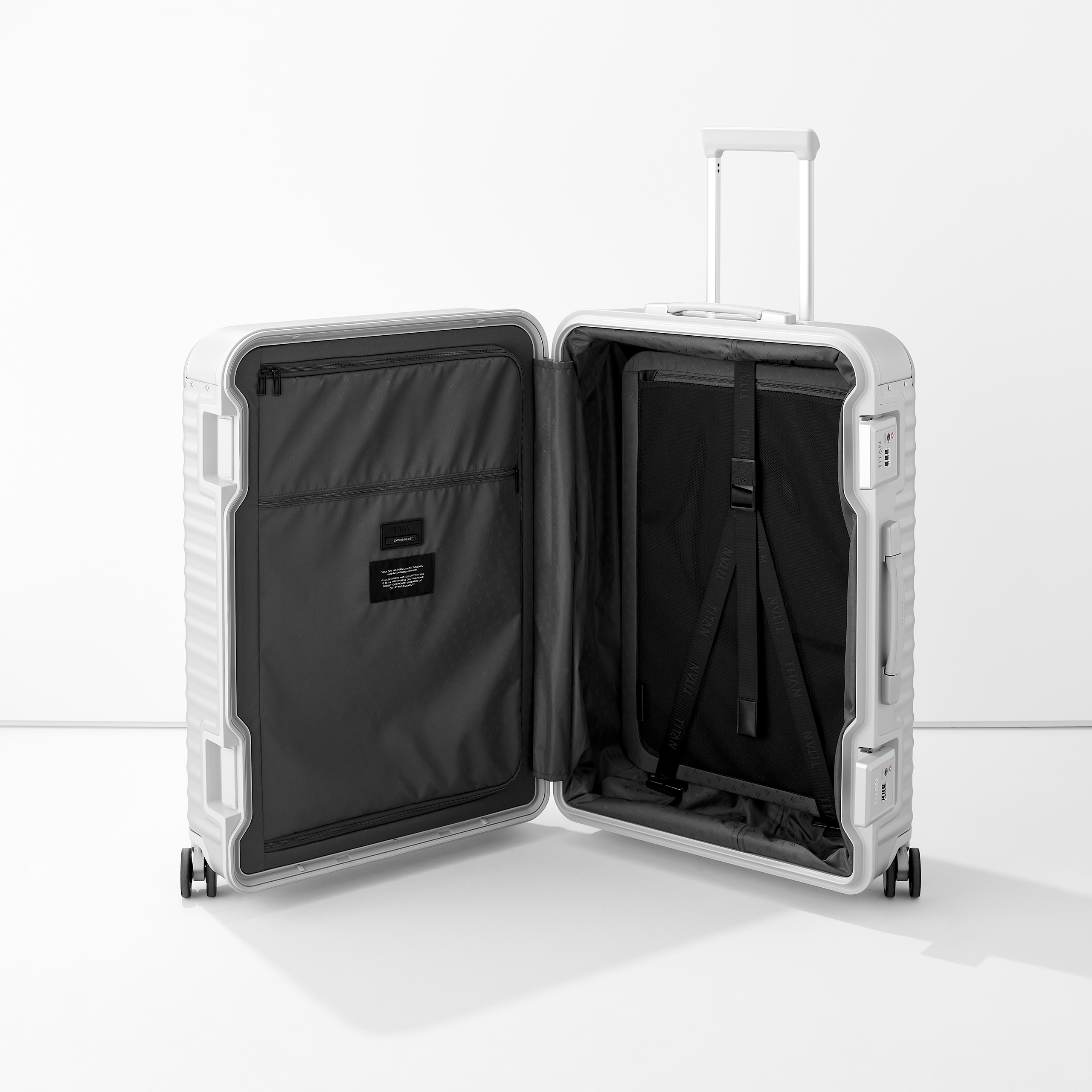 Moderner Aluminium-Koffer geöffnet mit Innenfächern und Packgurten Offener silberner Aluminium-Koffery mit schwarzen Innenfächern, Reißverschlusstasche und Packgurten, stehend auf hellen Boden