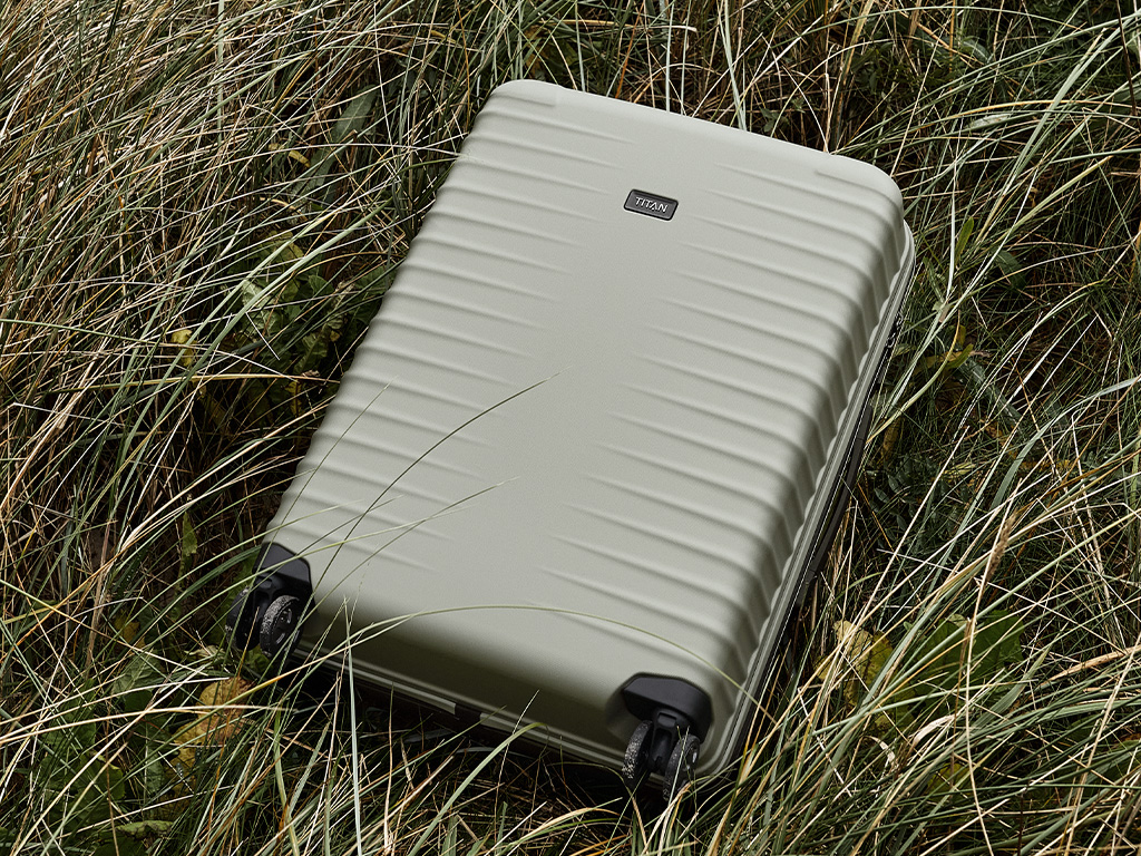 Valigia grigia con struttura a coste adagiata nell'erba alta