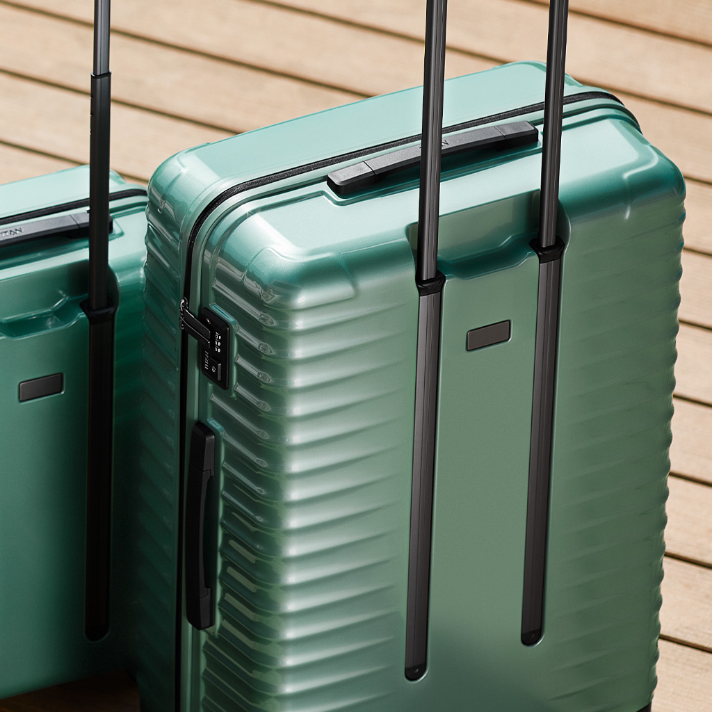 Due valigie rigide verdi con manici retrattili su base di legno