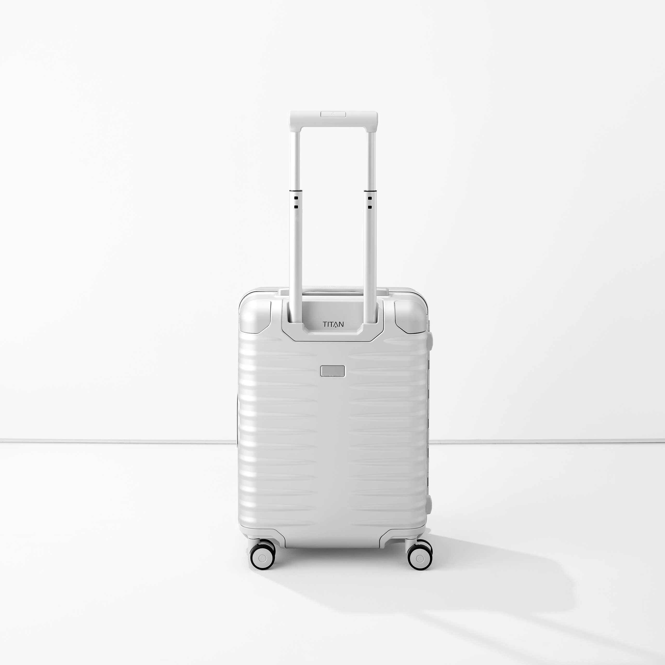 Moderner silberner Koffer von TITAN aus Aluminium mit Teleskopgriff und vier Rollen, freistehend in hellem Raum
